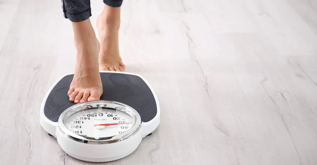 Woman measuring her weight using scales on floor
